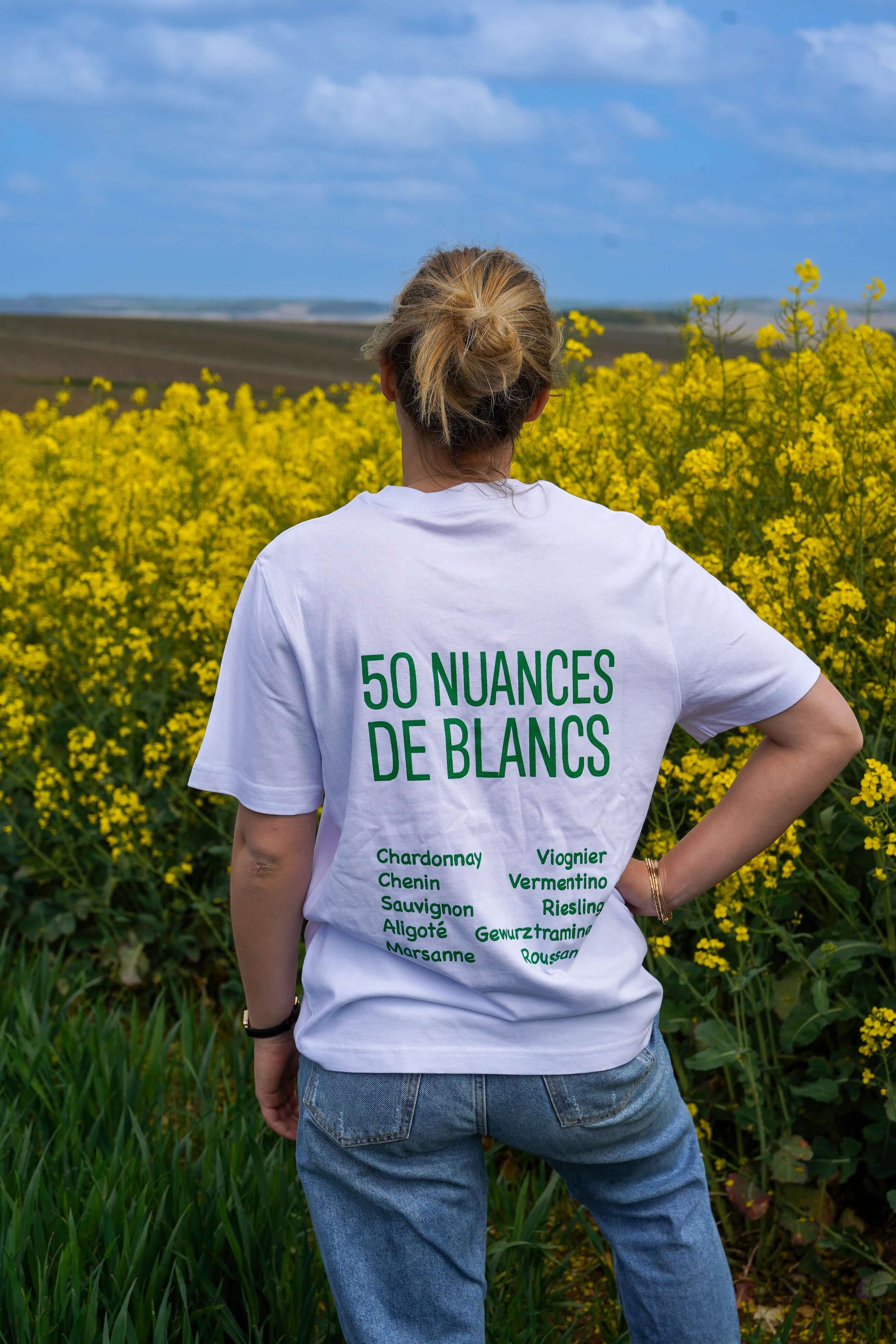 Image of T-shirt '50 Nuances de Blancs' en coton biologique, coupe décontractée, au milieu de fleurs jaunes.